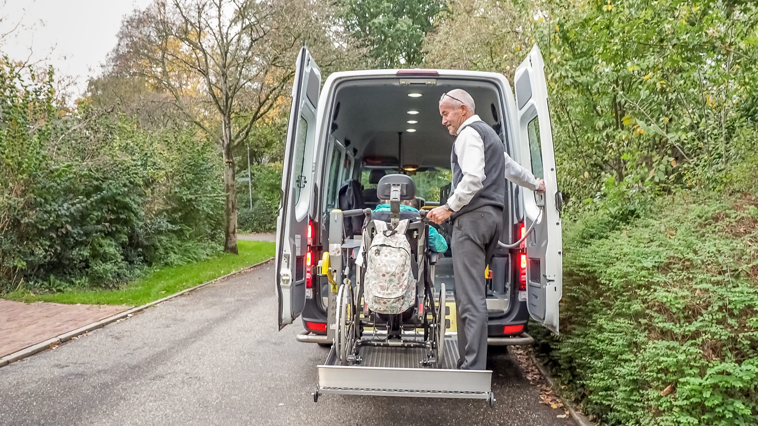 A senior retired man helping to transport disabled people